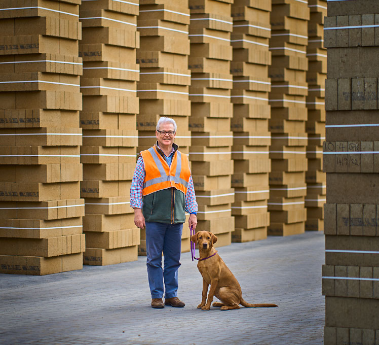 Giles de Lothiniere and pet dog standing in Lignacite yard.