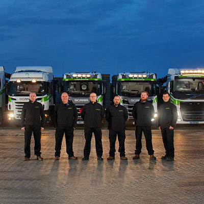 A line of transport drivers standing in front of their lorrys.